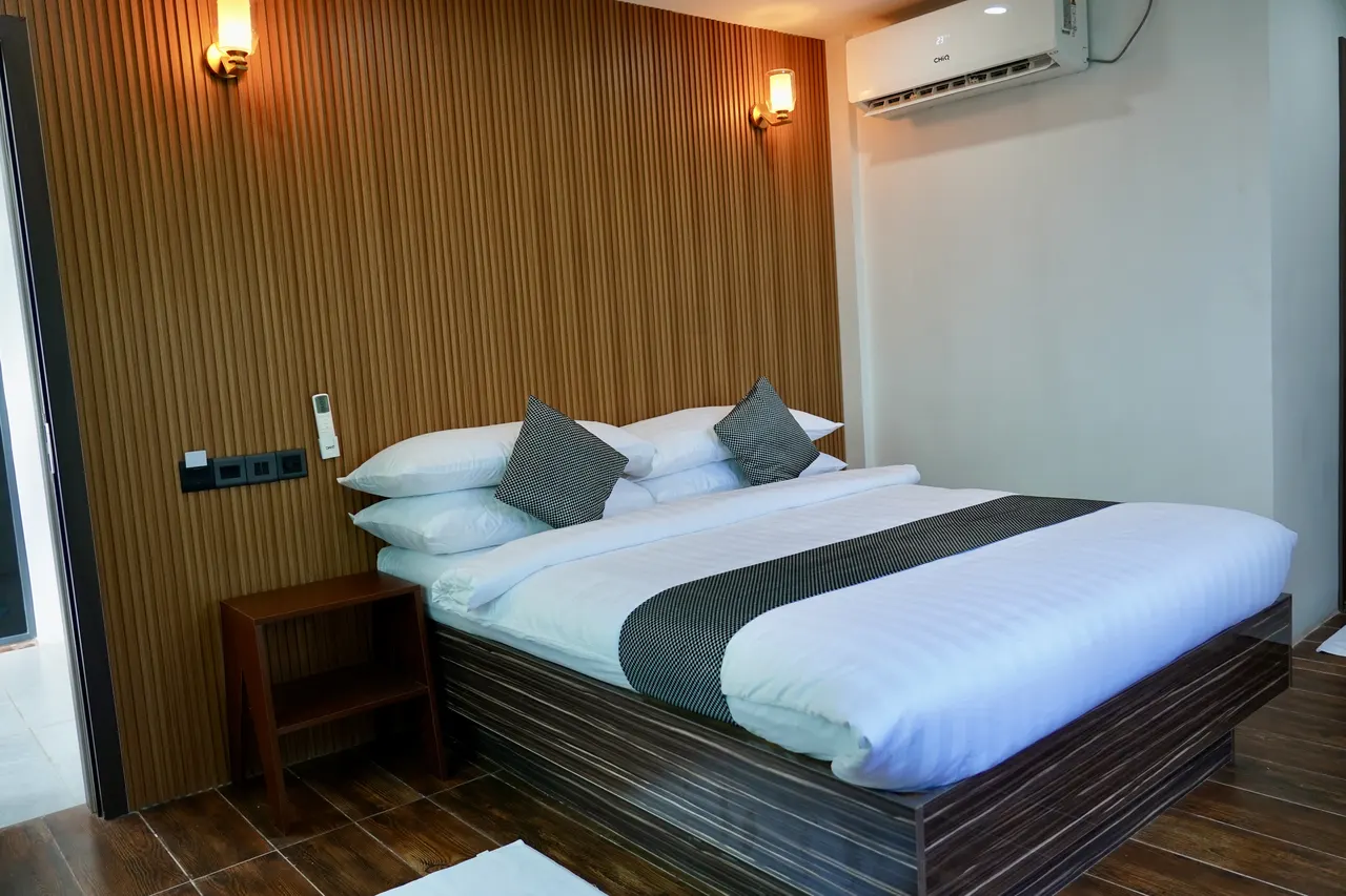 Double room at Cozy Art Dhangethi with timber-slat feature wall and wall lamps