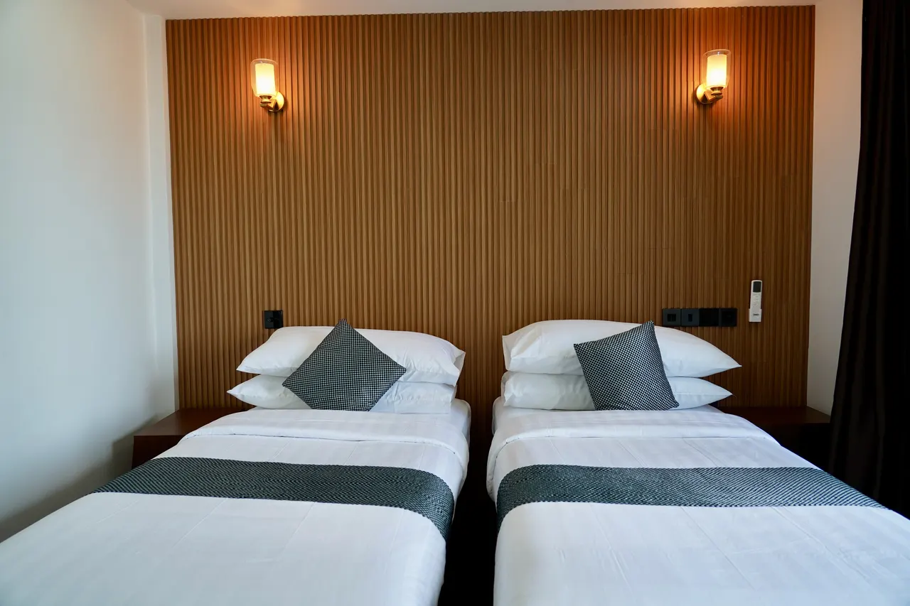 Twin room at Cozy Art Dhangethi with timber-slat headboard and two beds