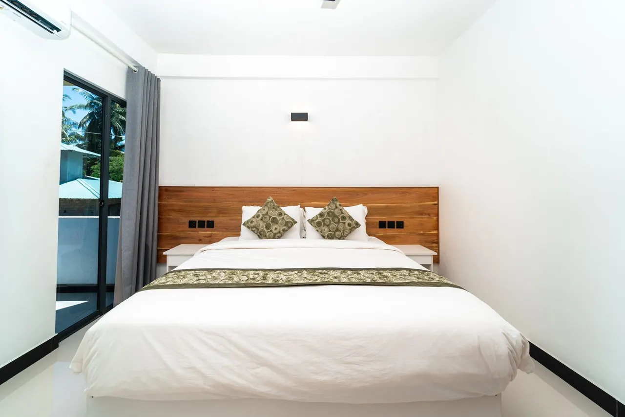 Double Deluxe room with large bed and balcony doors at Cozy Roots Fuvahmulah