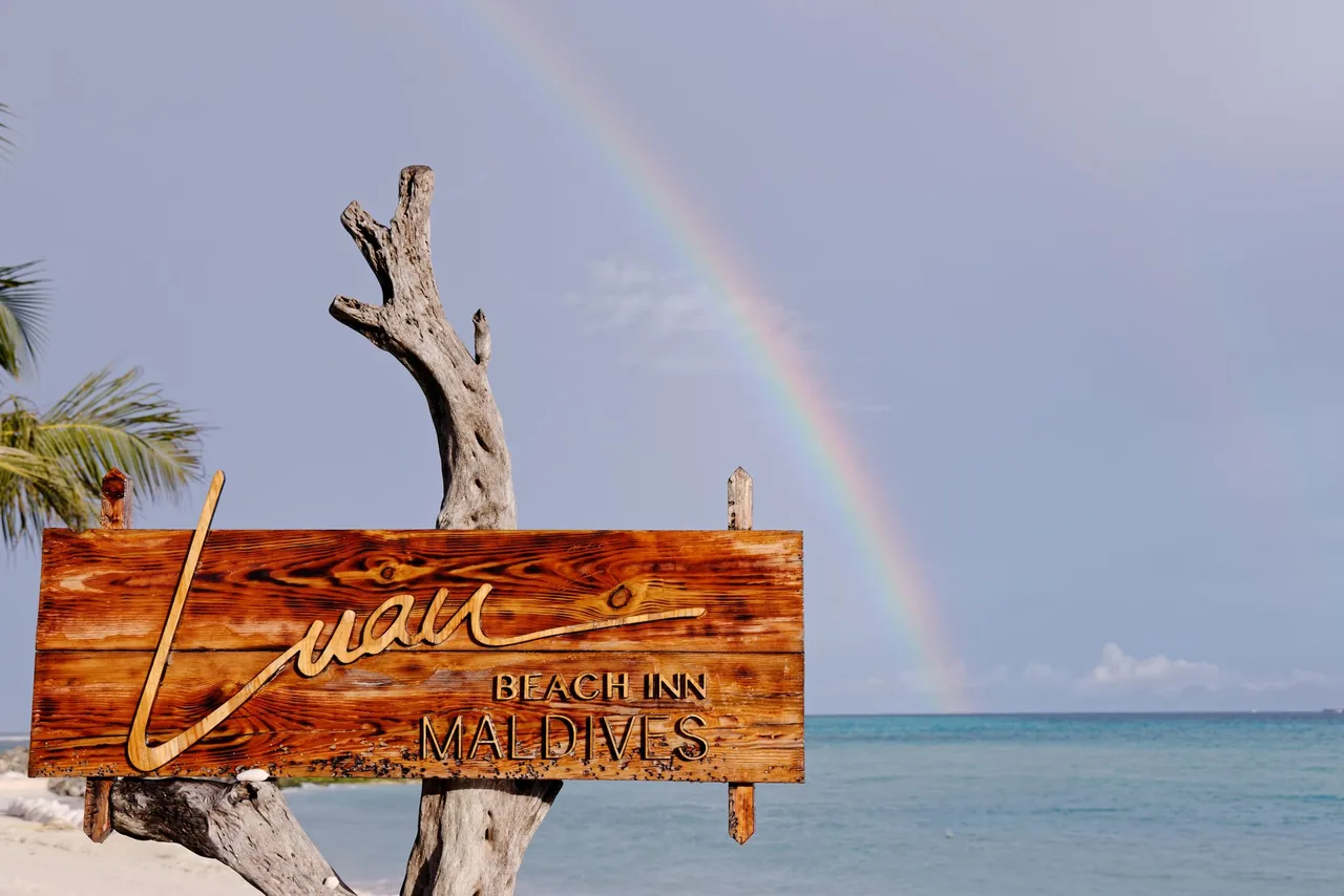 The Luau Beach Inn sign with a rainbow over the sea